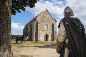 Templario visto desde atrás a lo lejos una capilla medieval