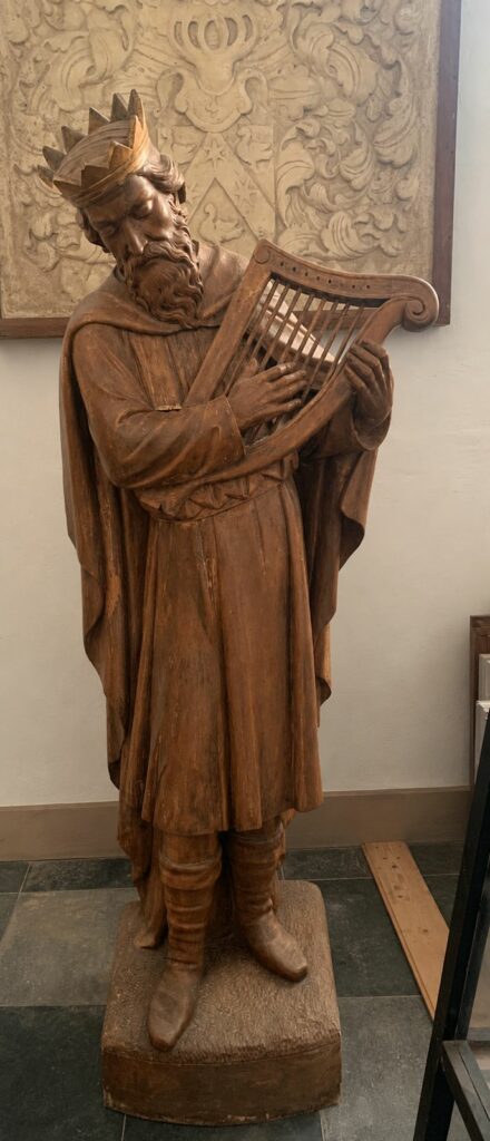 Koning David met harp – mensgroot houten beeld uit de Grote Kerk van Breda. David draagt een kroon en bespeelt een harp, als verwijzing naar de Psalmen en de lofzang op God.
