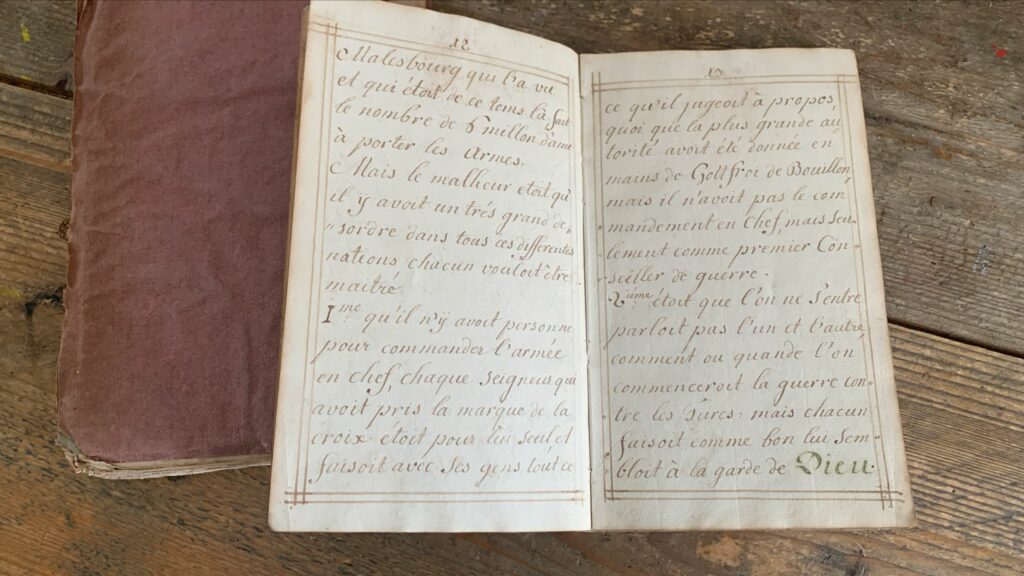 Openliggend 18e-eeuws Frans handschrift over de Eerste Kruistocht, gefotografeerd op een houten tafel.