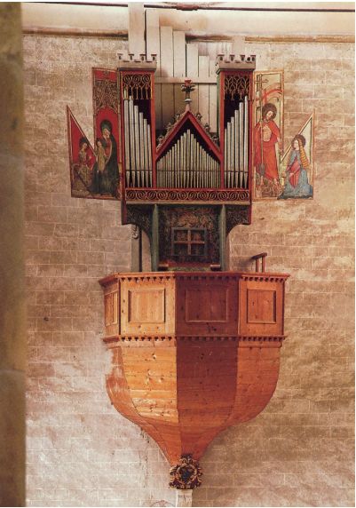 Vijftiende-eeuws orgel in de Basilique de Valère in Sion, hoog aan de kerkmuur geplaatst, met een houten onderbouw, gotische orgelkas, verticale pijpen en geopende beschilderde luiken met religieuze voorstellingen.